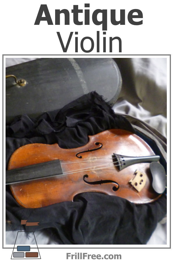 Picture of an old violin, being unwrapped from a black scarf.