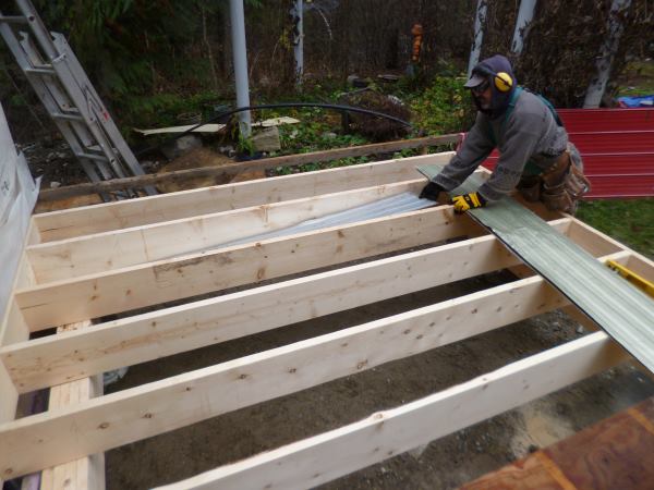 Metal siding is cut to size and put between each joist to hold the insulation